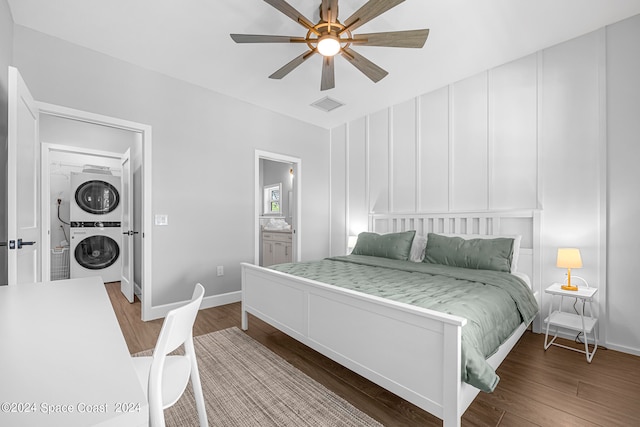 bedroom featuring ensuite bath, ceiling fan, stacked washer / dryer, and hardwood / wood-style flooring