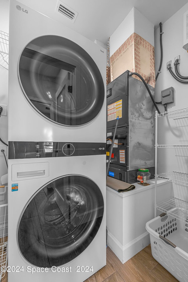 laundry room with wood-type flooring and stacked washing maching and dryer