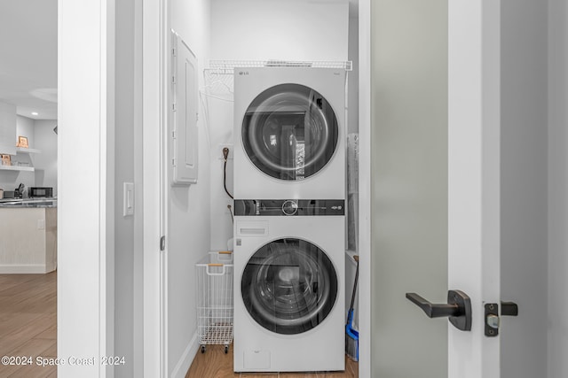 laundry room with stacked washer / dryer and light hardwood / wood-style flooring