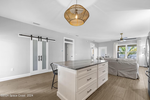 19 Vip Is Unit A, Grant, FL 32949 - kitchen featuring wood finished floors, a barn door, white cabinetry, and a ceiling fan