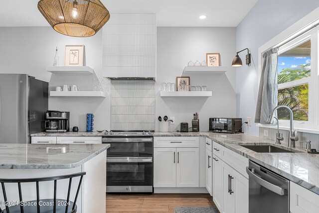 kitchen with white cabinetry, sink, stainless steel appliances, and light stone counters