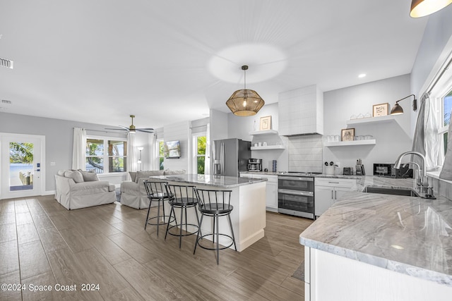 19 Vip Is Unit A, Grant, FL 32949 - kitchen with stainless steel appliances, open shelves, a sink, a breakfast bar area, and white cabinetry