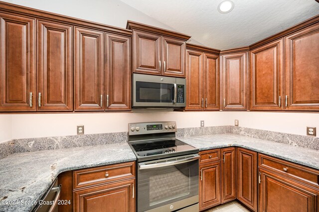 kitchen with light stone counters, a textured ceiling, and appliances with stainless steel finishes