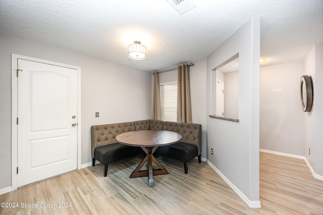 dining room with a textured ceiling and light hardwood / wood-style flooring