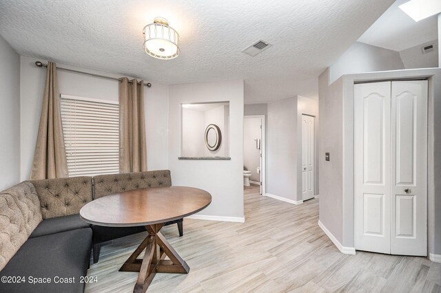 interior space with a skylight, a textured ceiling, and light hardwood / wood-style floors