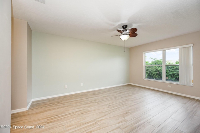 spare room featuring light wood-type flooring, ceiling fan, and a textured ceiling