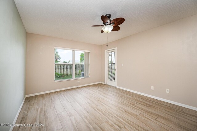 unfurnished room with light hardwood / wood-style floors, ceiling fan, and a textured ceiling