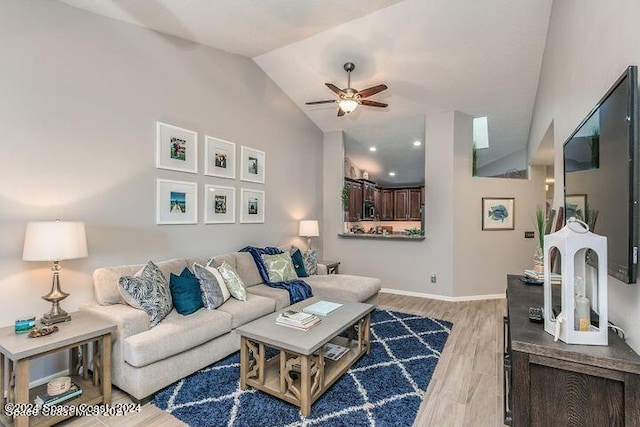 living room featuring ceiling fan, light wood-type flooring, and vaulted ceiling