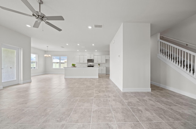 unfurnished living room featuring ceiling fan with notable chandelier and light tile patterned floors