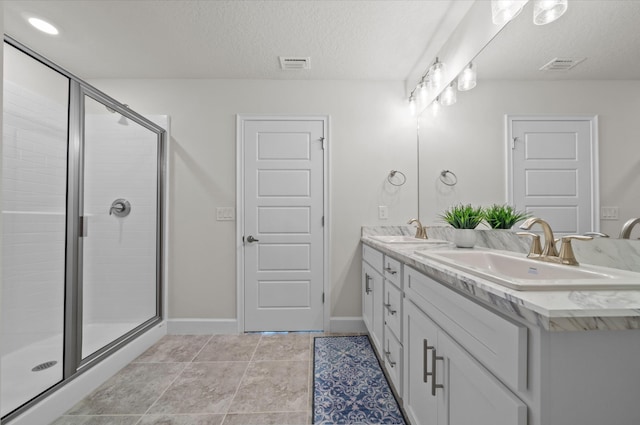 bathroom with a textured ceiling, tile patterned flooring, vanity, and a shower with door