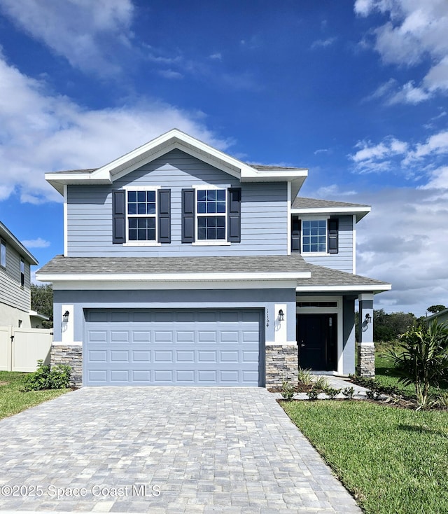 view of front of house featuring a garage, stone siding, fence, and decorative driveway