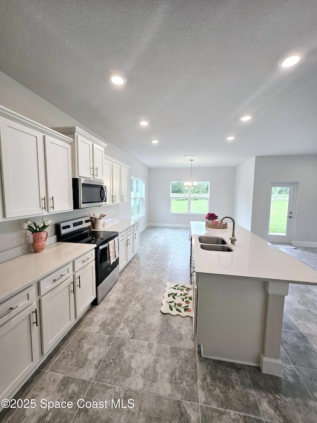 kitchen featuring a sink, a wealth of natural light, appliances with stainless steel finishes, and white cabinets