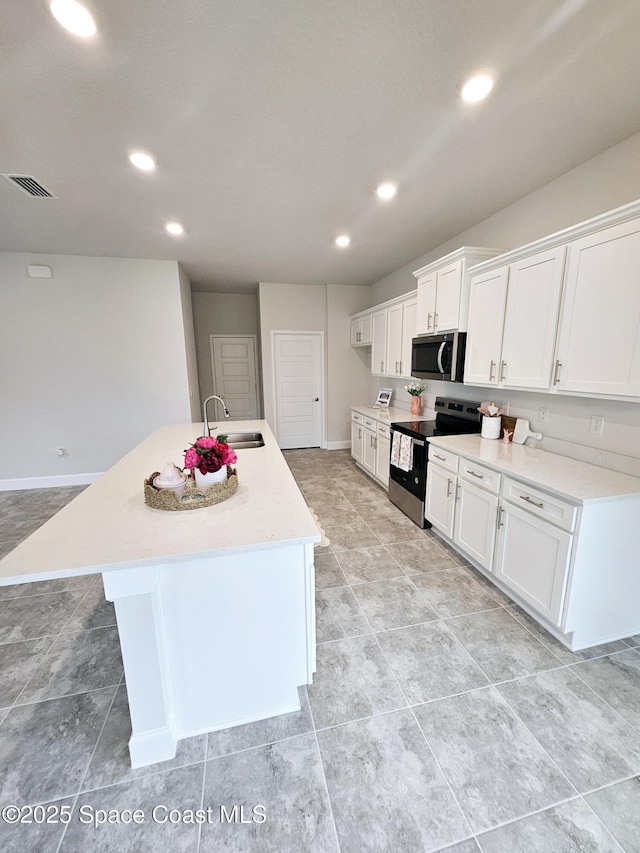 kitchen featuring visible vents, a center island with sink, a sink, white cabinetry, and appliances with stainless steel finishes