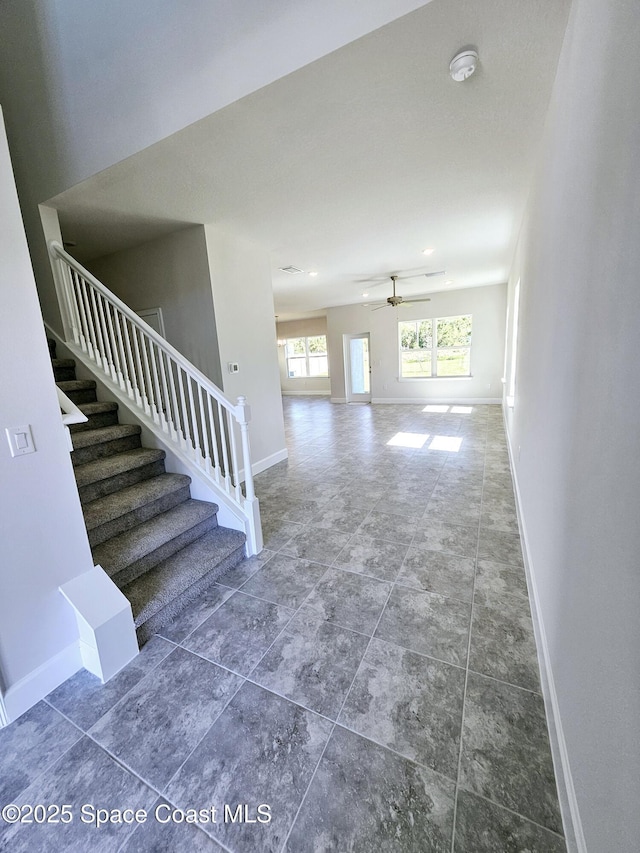 interior space featuring ceiling fan, stairs, and baseboards