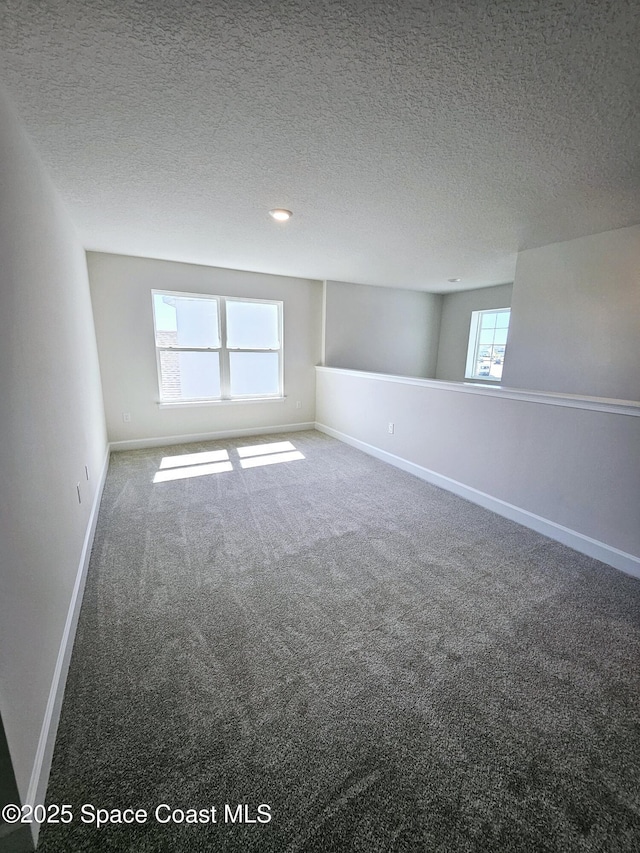 spare room featuring baseboards, carpet floors, and a textured ceiling