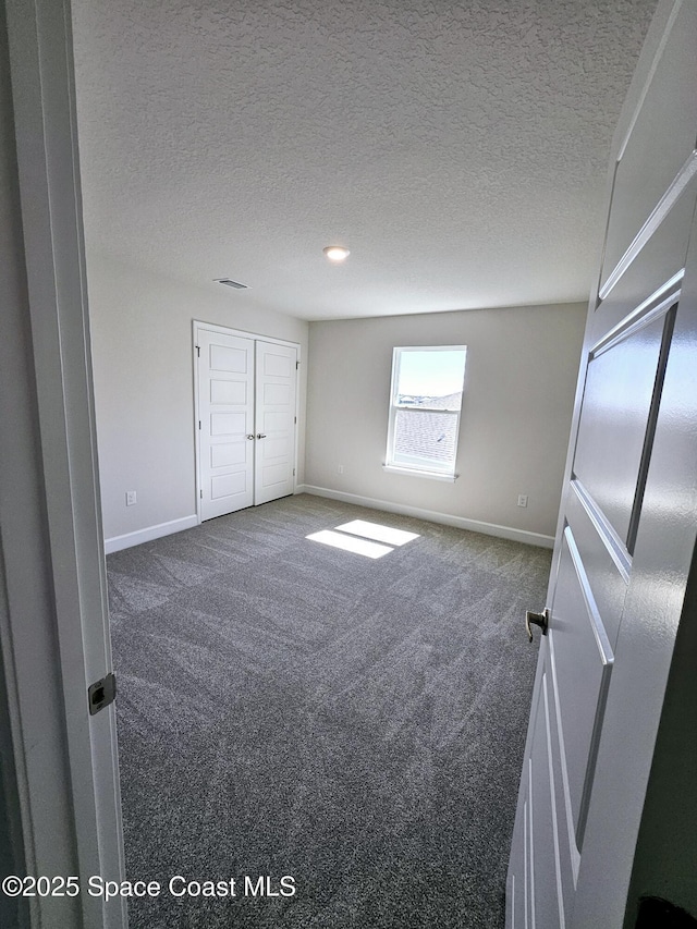 unfurnished bedroom with visible vents, carpet, baseboards, and a textured ceiling