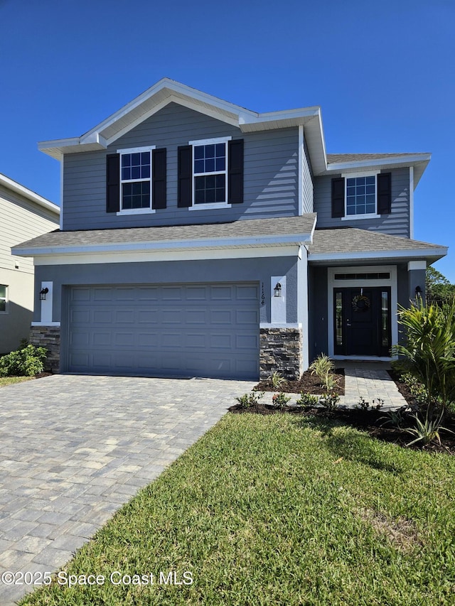 view of front of property with a garage, stone siding, and decorative driveway