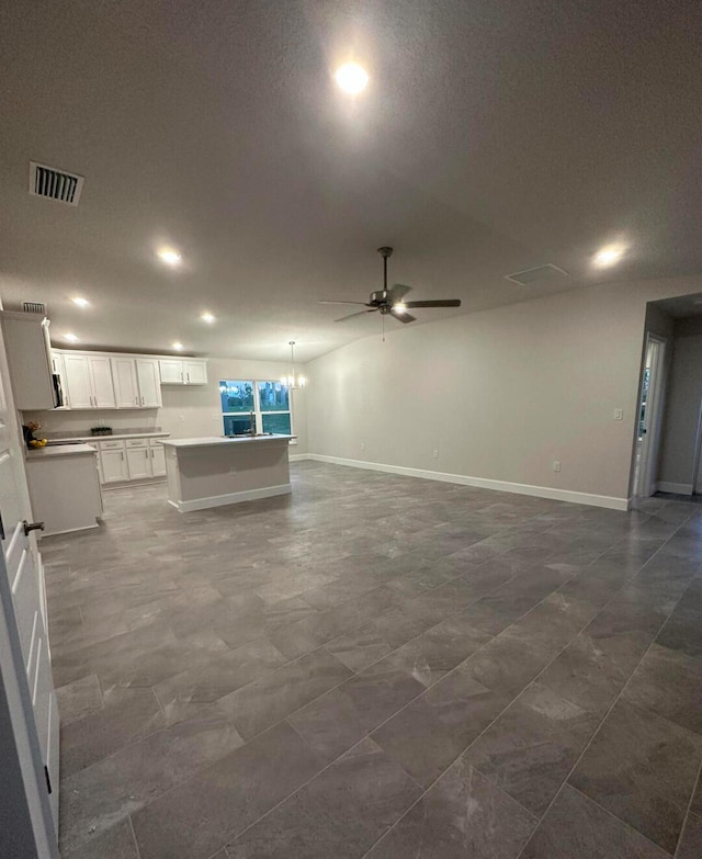 unfurnished living room featuring a textured ceiling and ceiling fan with notable chandelier