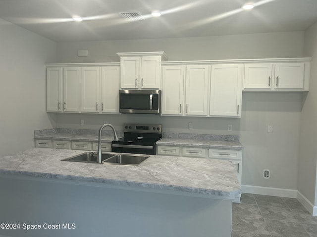 kitchen featuring electric range, a kitchen island with sink, light stone countertops, sink, and white cabinets