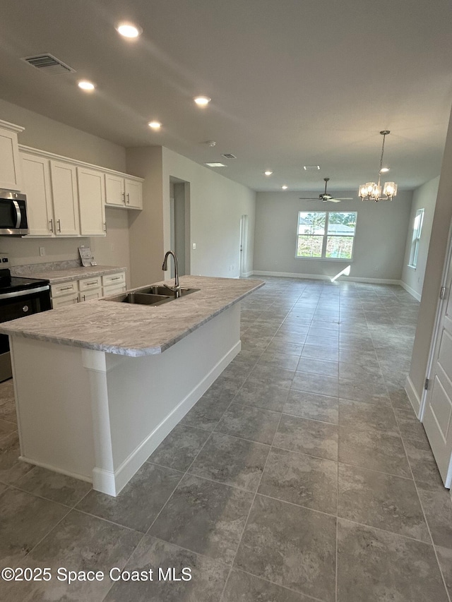 kitchen with recessed lighting, a kitchen island with sink, a sink, stainless steel appliances, and white cabinetry