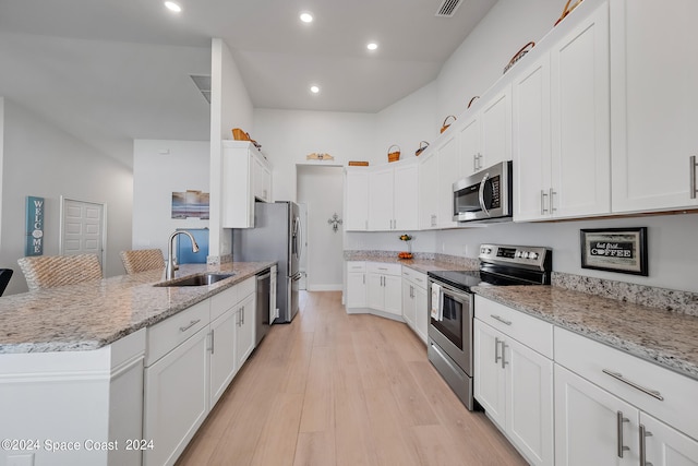 kitchen with light wood-type flooring, sink, stainless steel appliances, and white cabinets