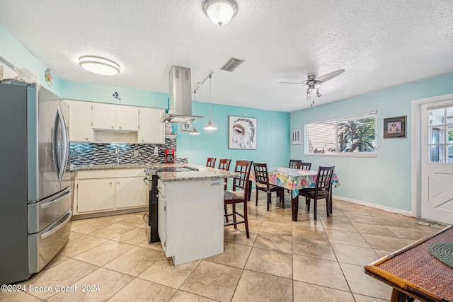 kitchen with white cabinetry, ceiling fan, stainless steel appliances, island exhaust hood, and decorative light fixtures