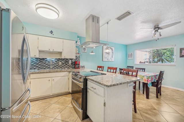 kitchen featuring light stone countertops, a textured ceiling, stainless steel appliances, island range hood, and a breakfast bar area