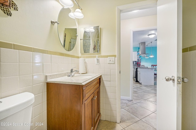 bathroom with tile patterned floors, vanity, toilet, and tile walls