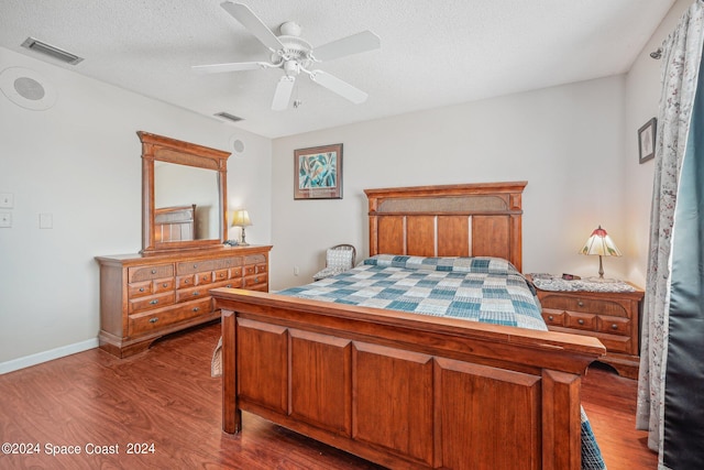 bedroom with hardwood / wood-style flooring, ceiling fan, and a textured ceiling