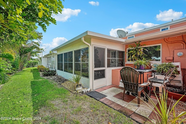 back of house featuring a sunroom, a patio area, and a yard