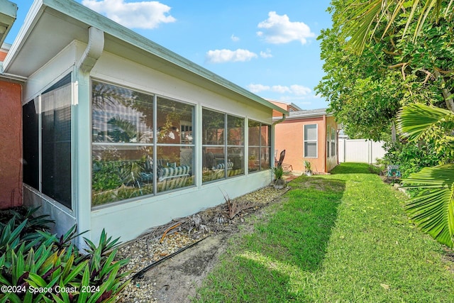 view of home's exterior featuring a sunroom and a lawn