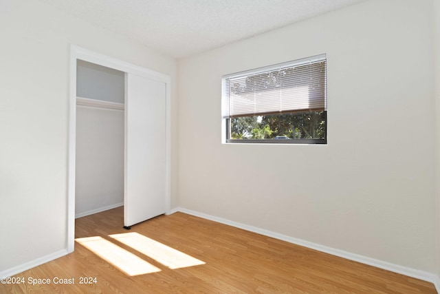 unfurnished bedroom featuring light hardwood / wood-style floors, a textured ceiling, and a closet