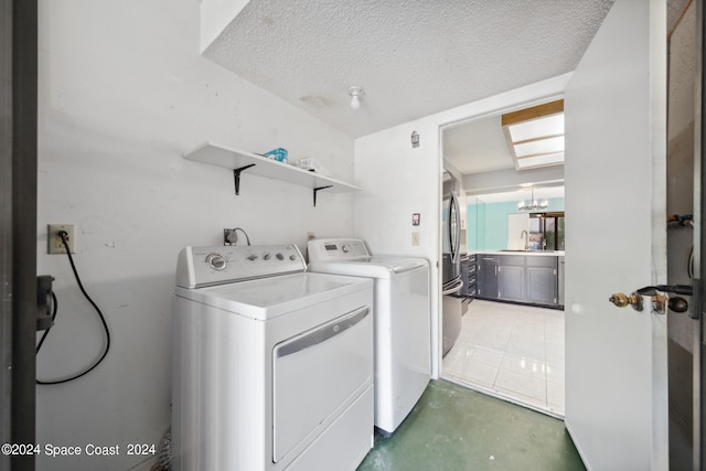 washroom with a textured ceiling, washing machine and dryer, and sink