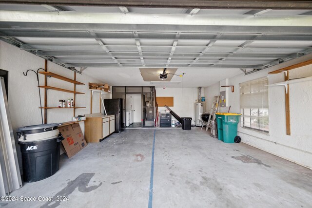 garage featuring water heater, black fridge, and a garage door opener