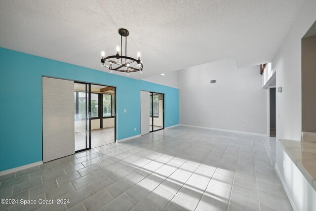 unfurnished room with a textured ceiling and a notable chandelier