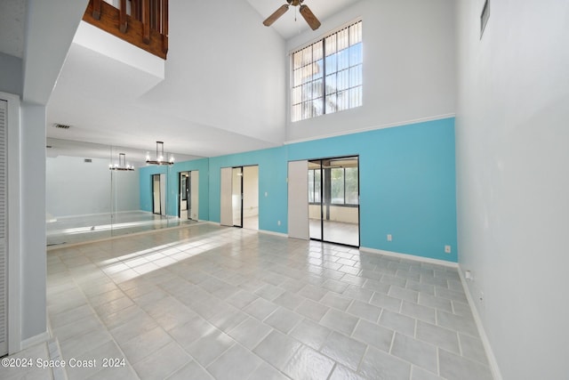 unfurnished living room featuring light tile patterned floors, ceiling fan with notable chandelier, a high ceiling, and a healthy amount of sunlight