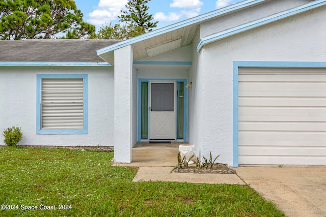 entrance to property with a garage and a lawn