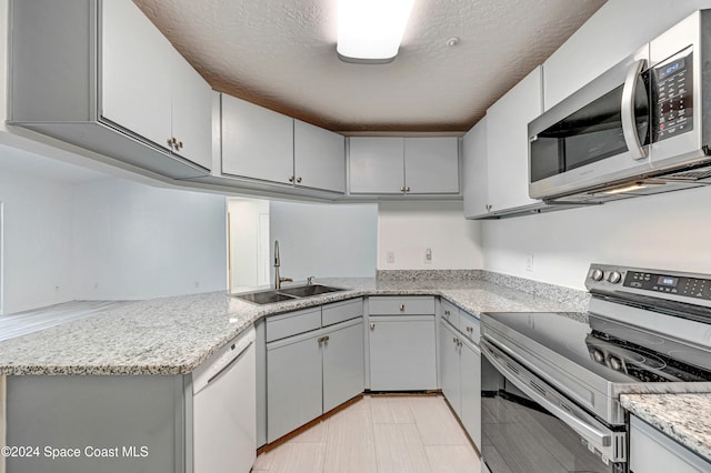 kitchen featuring kitchen peninsula, a textured ceiling, light stone countertops, sink, and stainless steel appliances