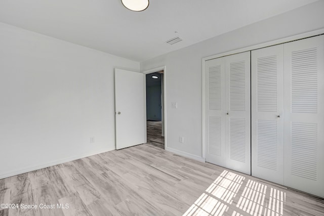 unfurnished bedroom featuring light hardwood / wood-style flooring and a closet