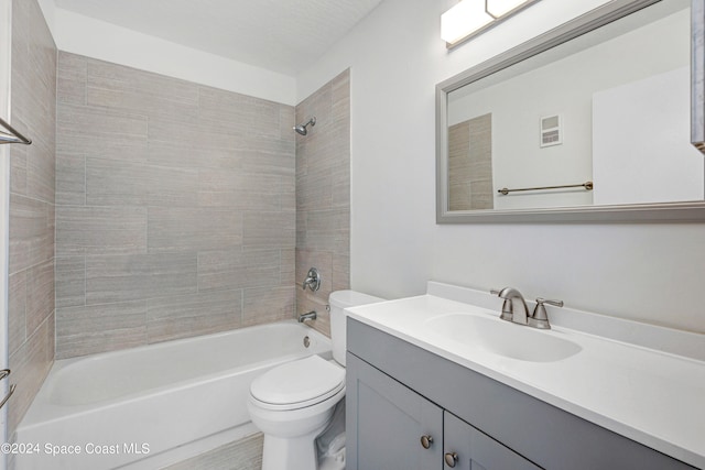 full bathroom featuring vanity, tiled shower / bath, and toilet