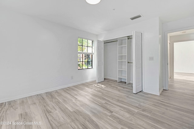 unfurnished bedroom featuring light hardwood / wood-style flooring and a closet