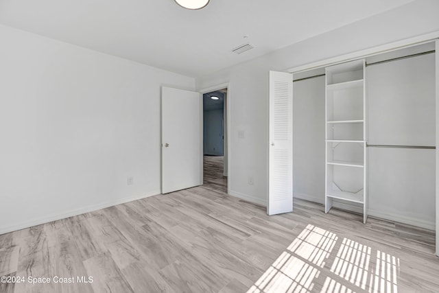 unfurnished bedroom with a closet and light wood-type flooring