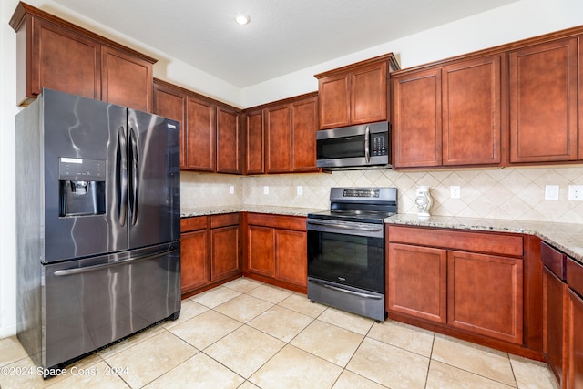 kitchen featuring light stone countertops, appliances with stainless steel finishes, light tile patterned floors, and decorative backsplash