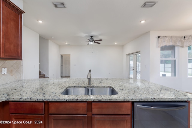 kitchen with light stone counters, tasteful backsplash, sink, ceiling fan, and stainless steel dishwasher