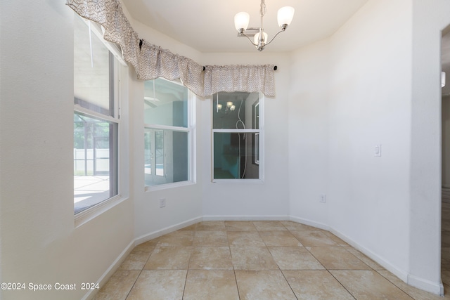 spare room with an inviting chandelier and light tile patterned floors