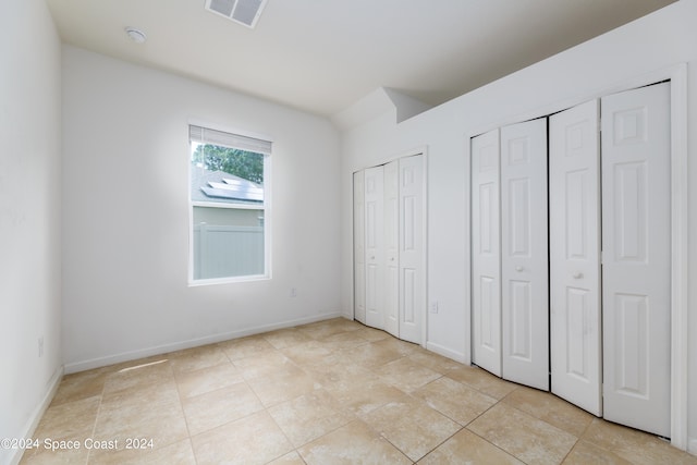 unfurnished bedroom with multiple closets and light tile patterned floors