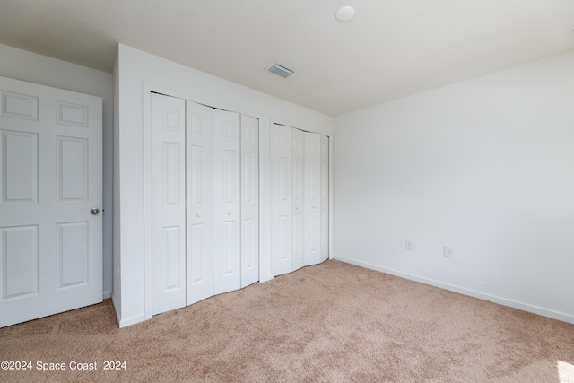 unfurnished bedroom with light carpet and multiple closets