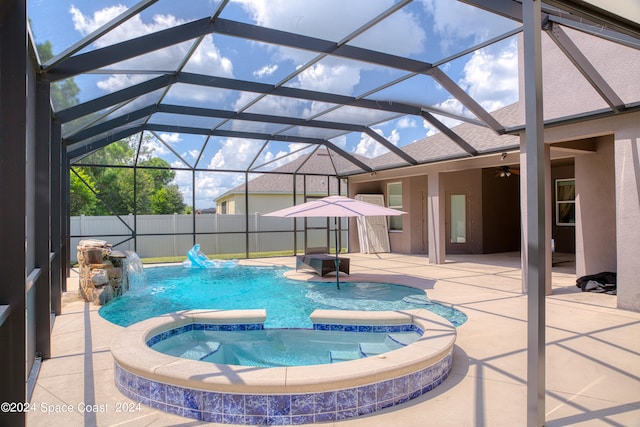 view of pool featuring pool water feature, a patio, glass enclosure, and an in ground hot tub