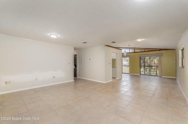 empty room featuring lofted ceiling, light tile patterned floors, and a textured ceiling