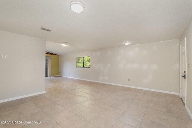 tiled empty room featuring lofted ceiling